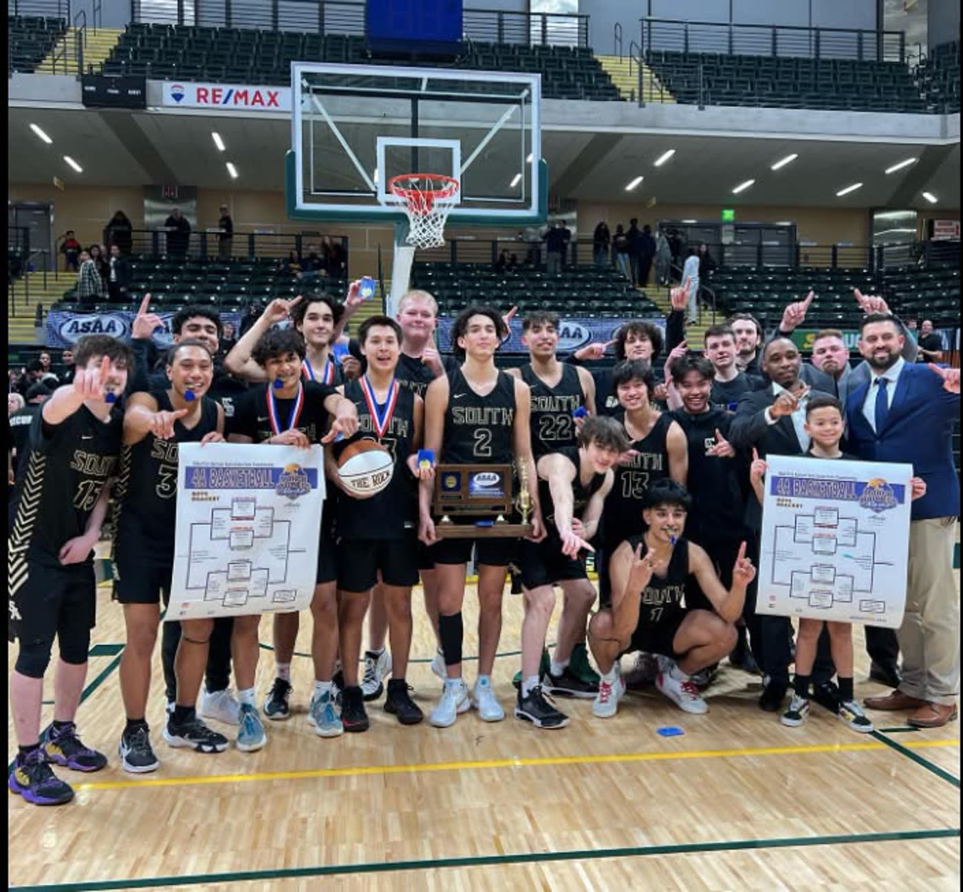 South Anchorage players celebrating on court with the tournament bracket and trophy