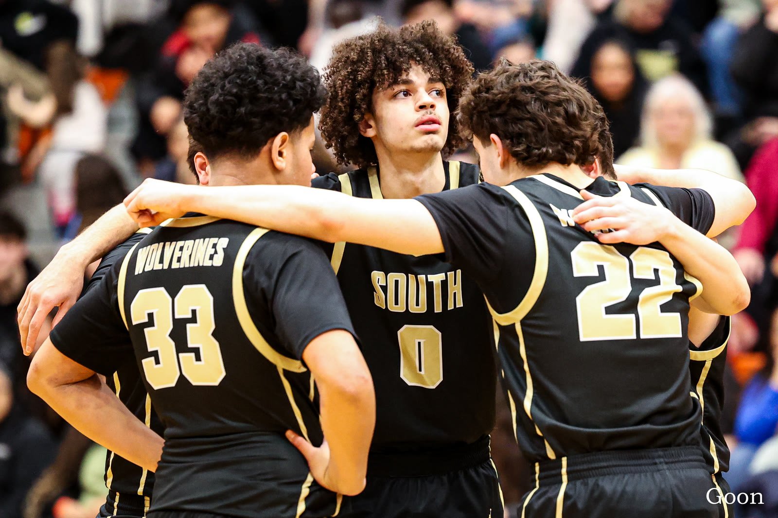 South Anchorage players arm in arm in a huddle during a game